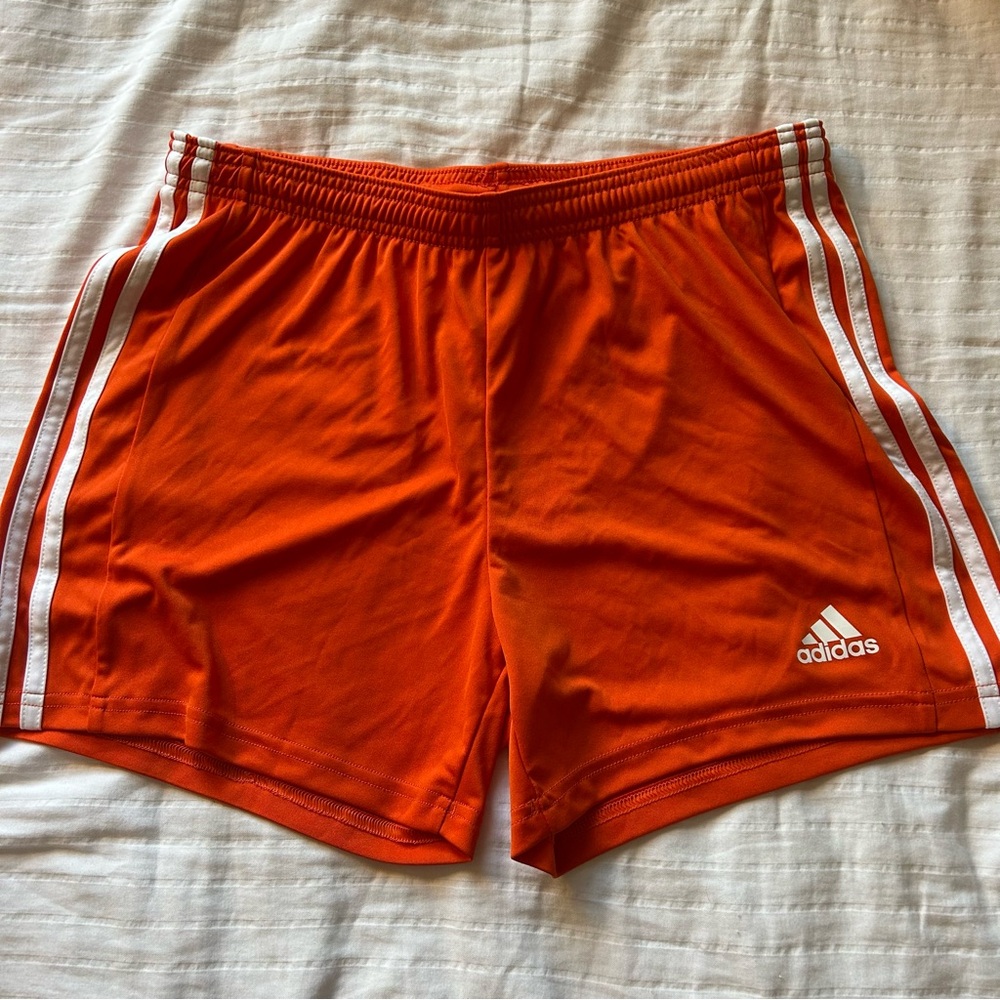 Orange Adidas shorts with white stripes
